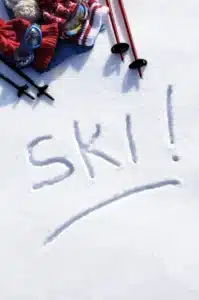 Matériel de ski posé sur la neige avec ski écrit en grand sur la neige